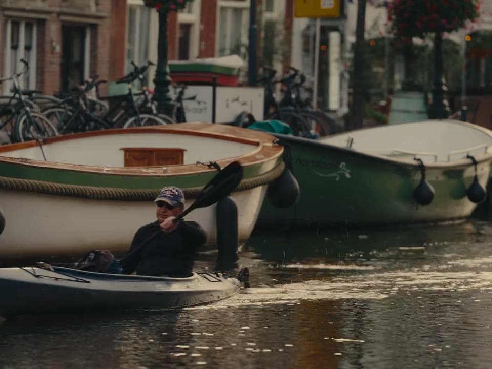 Een kajakker op de gracht langs de bootjes
